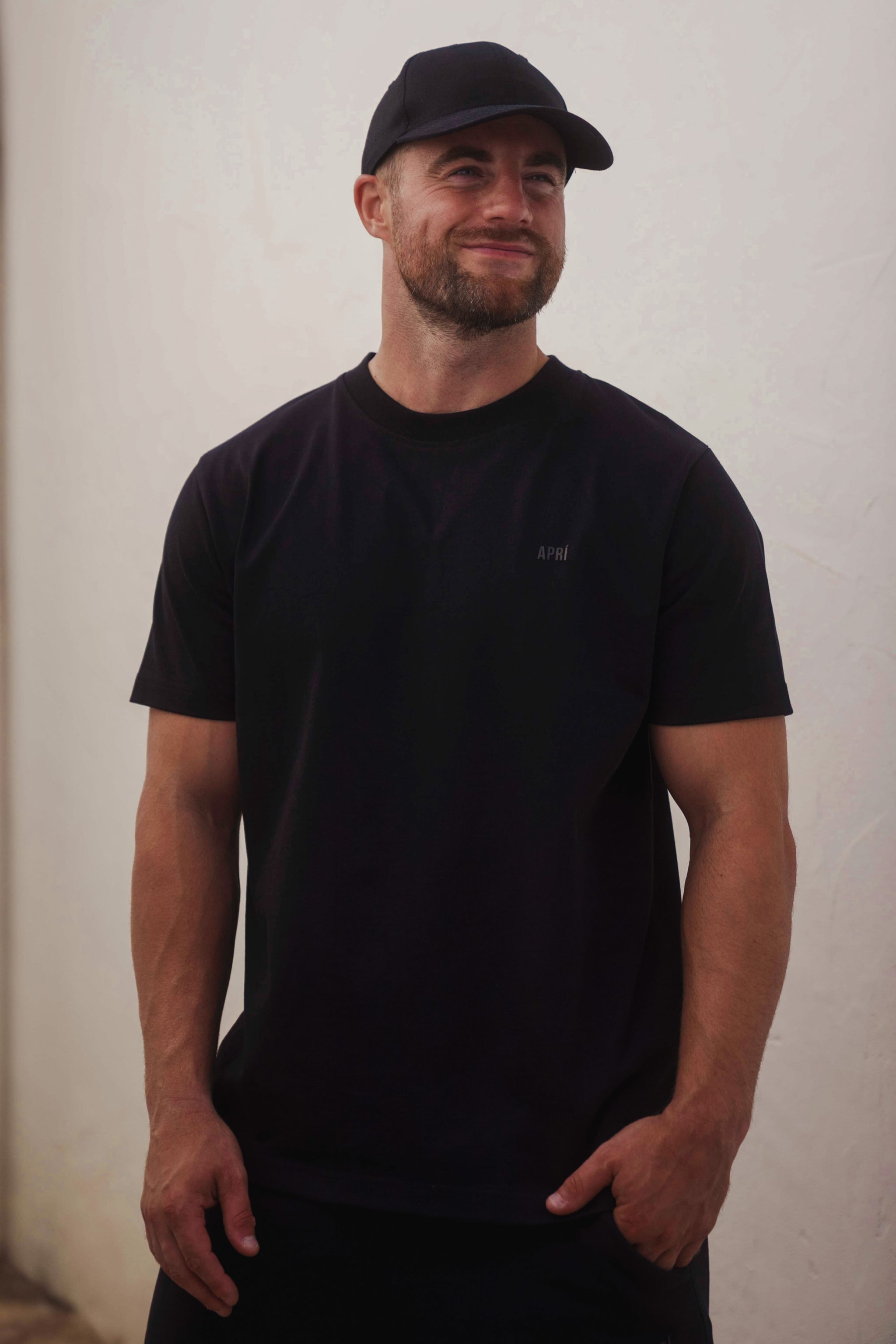 Man wearing a black t-shirt and cap against a plain background